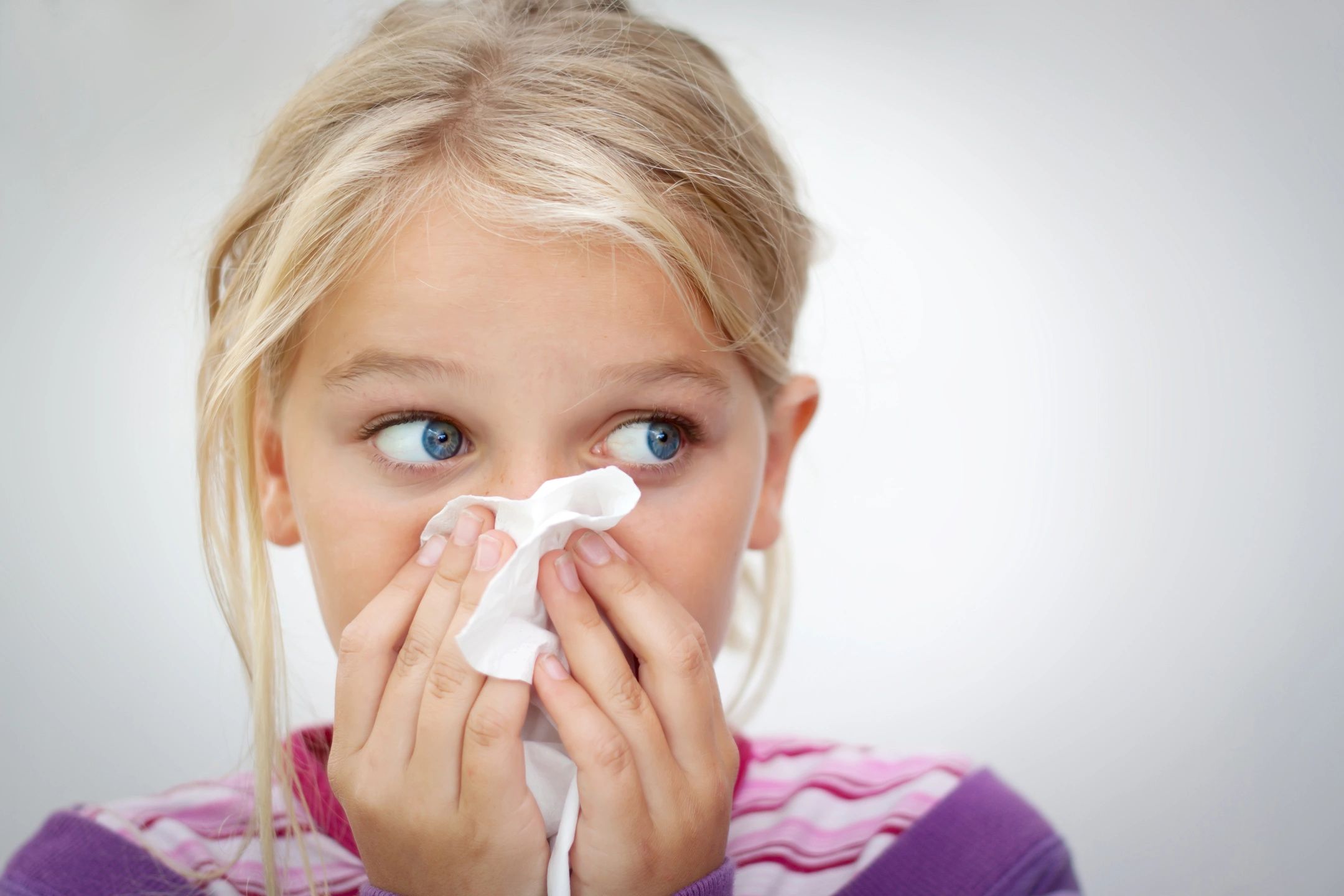 Child blowing their nose looking off to the side