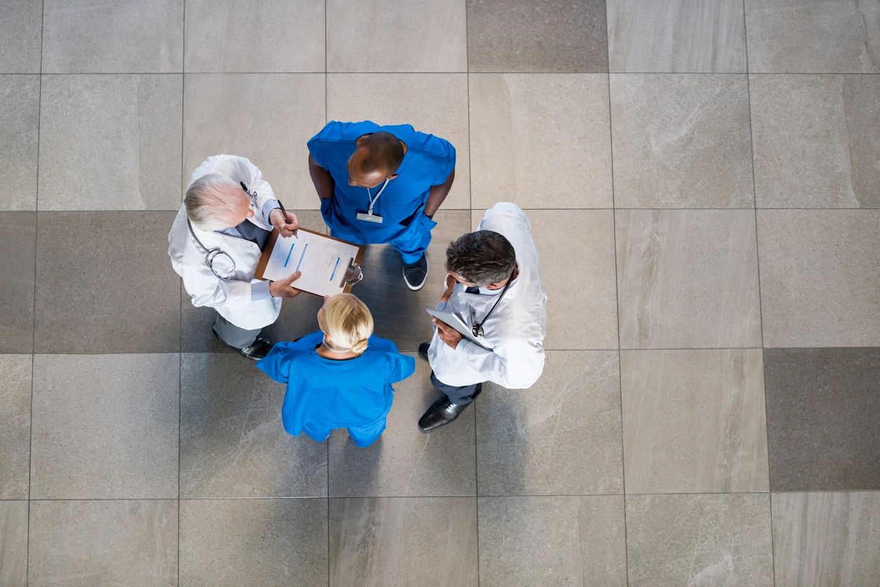 Four people in scrubs and lab coats talking as seen from above.